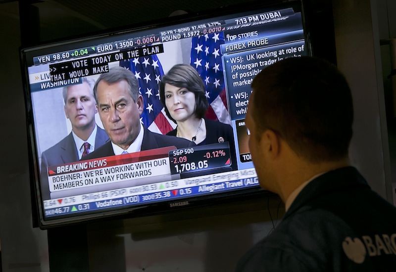 Specialist Frank Masiello watches a television monitor on the floor of the New York Stock Exchange showing a Washington news conference by House Speaker John Boehner, Tuesday, Oct. 15, 2013. Leaders in the House of Representatives and Senate were negotiating separate but similar plans Tuesday to reopen the U.S. government and prevent a default on American debt that economists say could tip the global economy back into recession.
