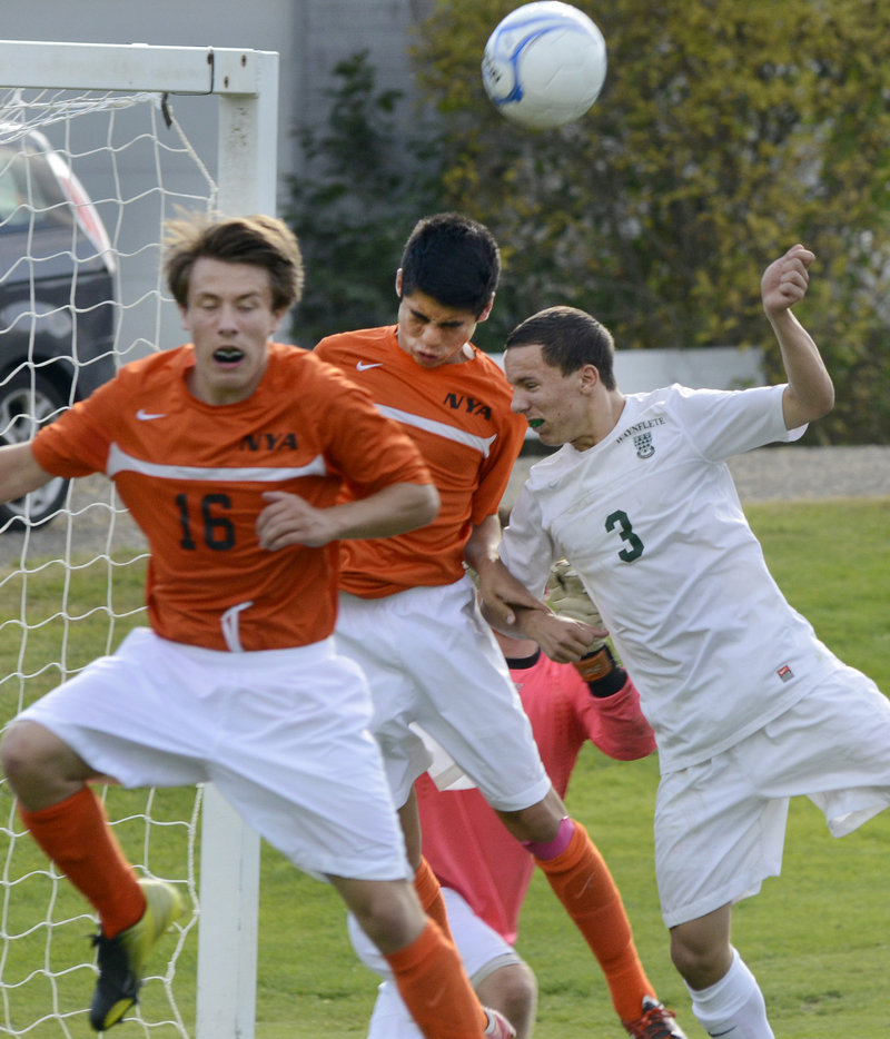 Xander Bartone of North Yarmouth Academy heads the ball away from the net Wednesday between his teammate, Jeremy Thelven, 16, and Harry Baker-Connick of Waynflete.