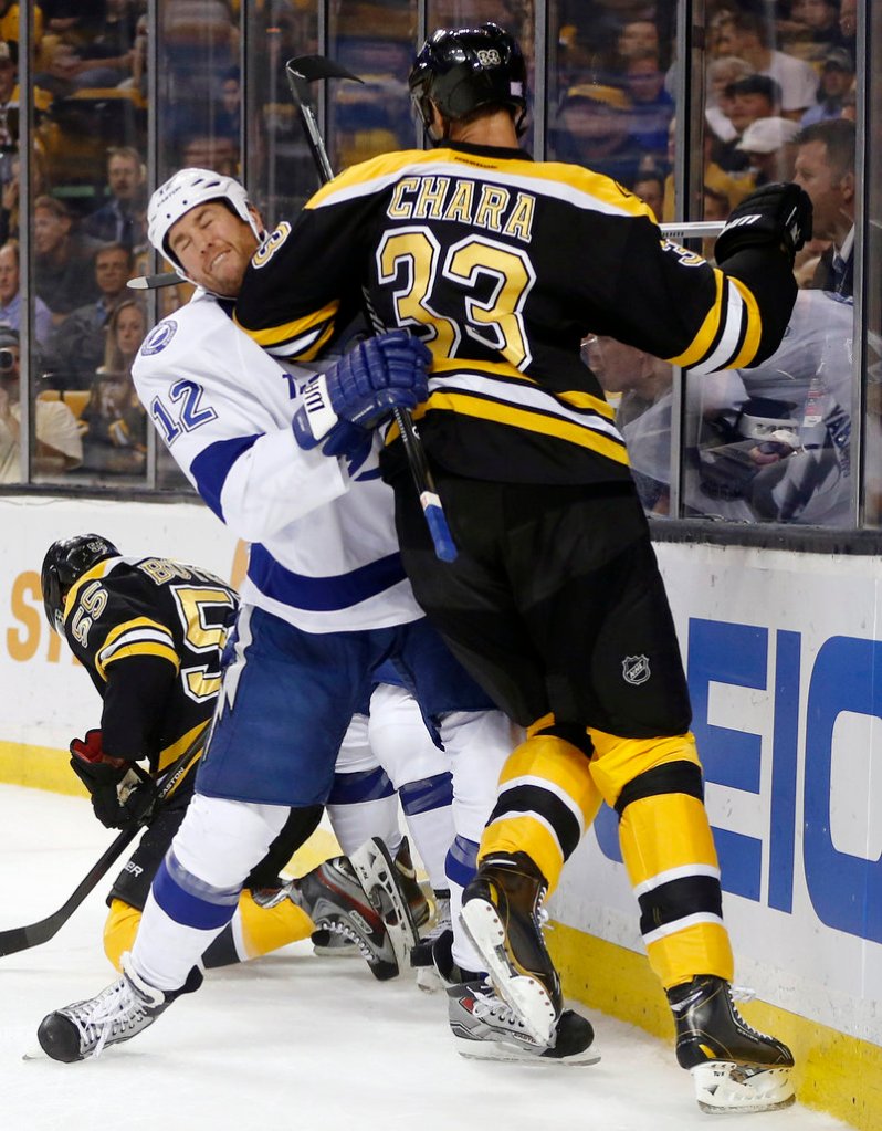 Boston defenseman Zdeno Chara towers over Tampa Bay’s Ryan Malone during first-period action of Thursday night’s season opener in Boston, won by the defending conference champion Bruins.