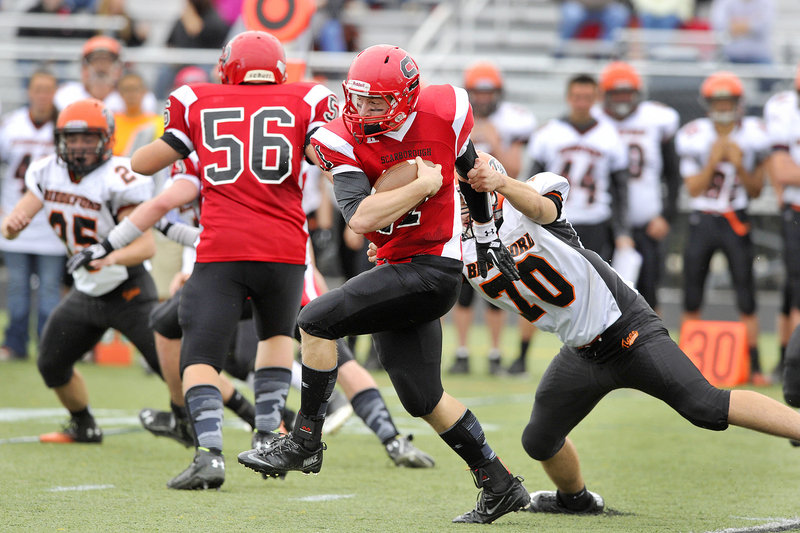 Scarborough quarterback Ben Greenberg pulls away from Peter Lekakos of Biddeford and scampers for a first down Saturday during Scarborough’s 41-21 victory at home.