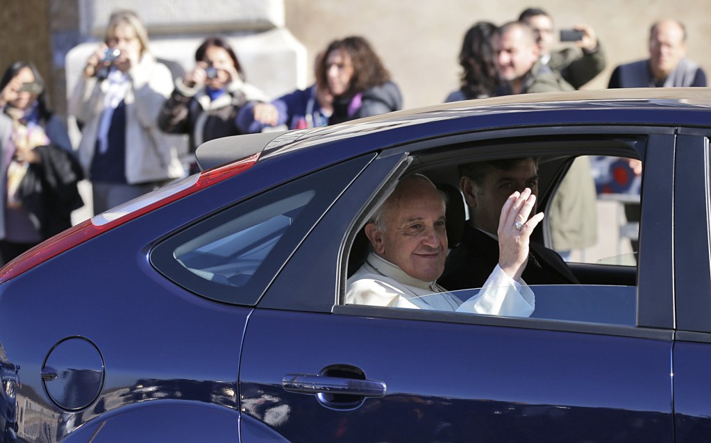 Pope Francis blesses the faithful from the back seat of his car as he leaves the Quirinale Presidential Palace in Rome after meeting with Italian President Giorgio Napolitano on Thursday. Pope Francis traveled across town Thursday for his first state visit with the Italian president, a traditionally pomp-filled ceremony that the simple pontiff defused by declining a mounted presidential guard escort and traveling in his own Ford Focus instead.