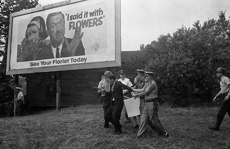 In this Sept. 4, 1963 file photo, police wrestle with an unidentified white man near a billboard after a demonstration at the newly-integrated Graymont Elementary School in Birmingham, Ala. On Duty Officer Standing Looking Away