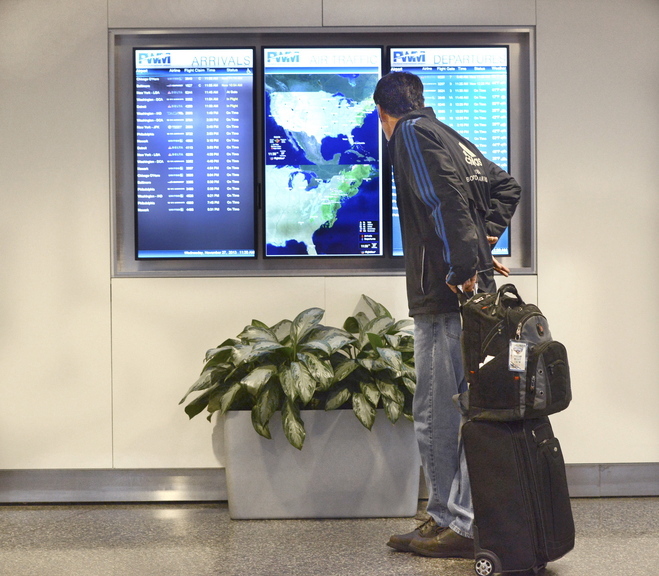Sumner Thompson of Phippsburg checks to make sure his Portland International Jetport flight is on time Wednesday. “I fly every week, and this is quiet for even a normal weekday,” Thompson said.