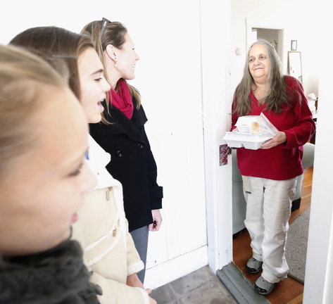 Carol Roberts of Biddeford holds the Thanksgiving meals that volunteers Abbigail Fournier, left, and her sister Allyson, center, and Jennifer Watson delivered to Roberts as part of Most Holy Trinity Church’s holiday effort.