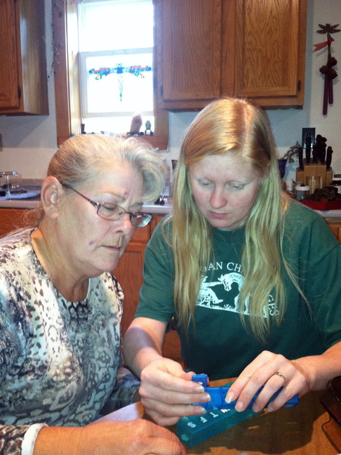 Amanda Sheppard, right. helps Anette Adams organize her pills at Adams’ home in New Haven, Vt.