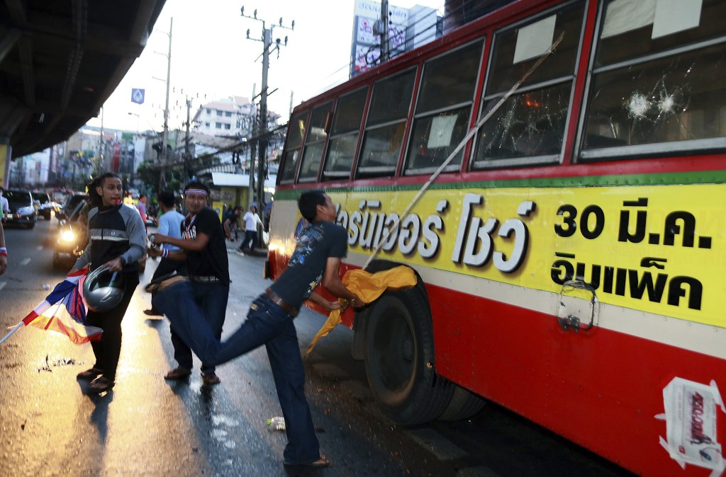 Anti-government protesters attack people they suspected of supporting the current Thai government on the bus in Bangkok,Thailand Saturday, Nov. 30, 2013. A mob of anti-government protesters smashed the windows of a moving Bangkok bus Saturday in the first eruption of violence after a week of tense street protests.