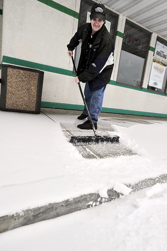 Bob Prevost, general manager of D’Angelo Sandwich Shop in North Windham, sweeps the first snow of the season from the entryway to his shop.