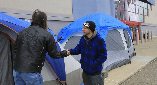 Campers Tony Avitar, left, and Jonas Allooh greet each other Tuesday at their tents outside of a Best Buy store in Cuyahoga Falls, Ohio, as they hope to be among the first through the doors to score Black Friday shopping bargains.