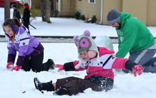 Audree Todd, left, gathers up a snowball to toss at sister Kensie, center, during a snowman-building session with their dad, Casey, at their home in Lawton, Okla., Sunday. The same storm is predicted to move into Maine on Wednesday, but mostly will drop rain instead of snow.