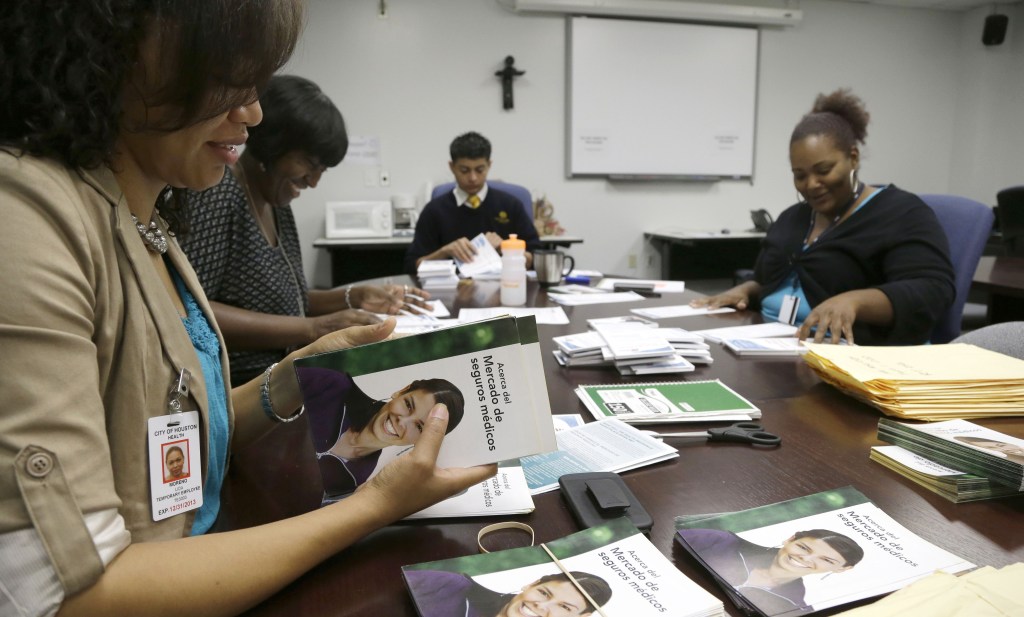 Houston city employee Lida Moreno, left, and colleagues count out Spanish language brochures for Enroll America in preparation for door-to-door distribution. Houston is trying to reach more than 1 million people who don’t have health insurance.