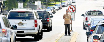 A man panhandles last July on a median at Marginal Way and Forest Avenue.