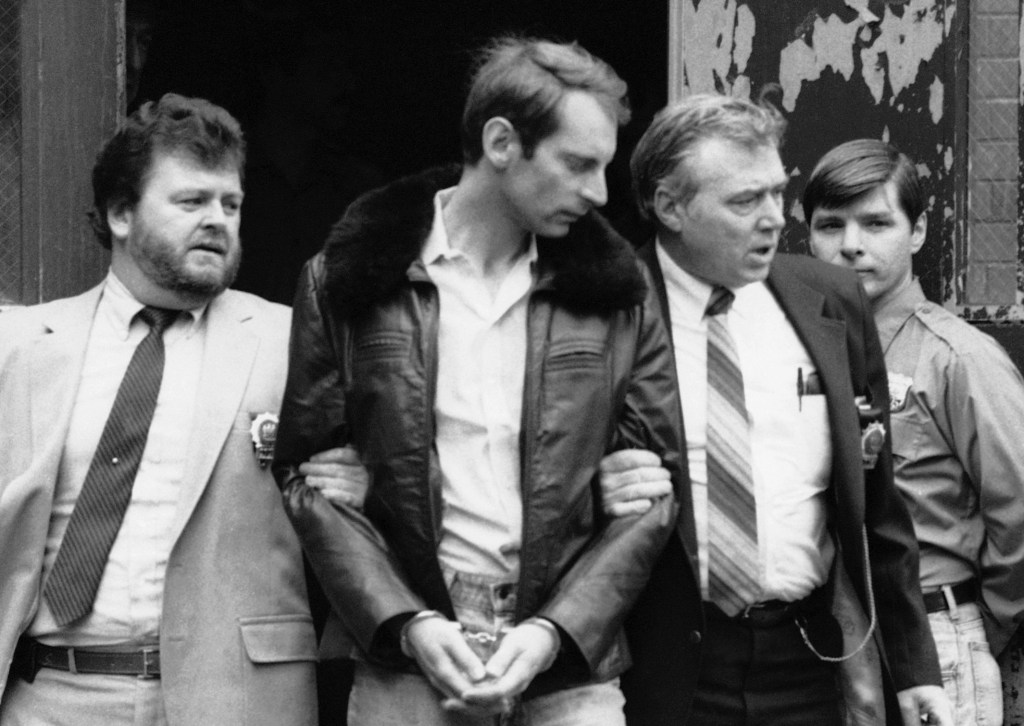 Subway vigilante Bernhard Goetz, second from left, is escorted by police officers as he is taken out of criminal court in New York on Jan. 16, 1985.
