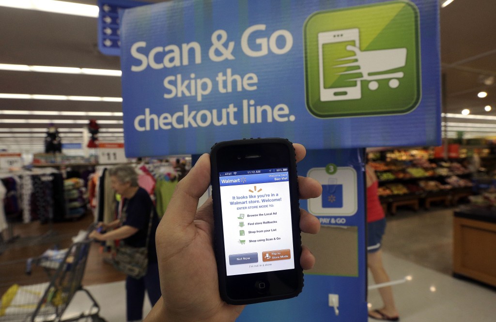 A Wal-Mart representative demonstrates a Scan & Go mobile application on a smartphone at a Wal-Mart store in San Jose, Calif. Wal-Mart is trying to make its mobile app an indispensable tool for customers shopping in its stores. The feature lets customers scan their items as they shop in the aisle and then pay at a self-service register.