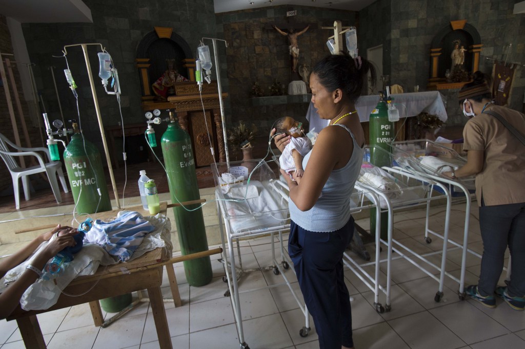 Nanette Salutan holds her baby son, Bernard, in her arms in front of the altar of a Catholic chapel inside the Eastern Visayas Regional Medical Center in Tacloban, Philippines on Saturday. The chapel is now being used to care for infants after Typhoon Haiyan destroyed the original facility of the hospital.