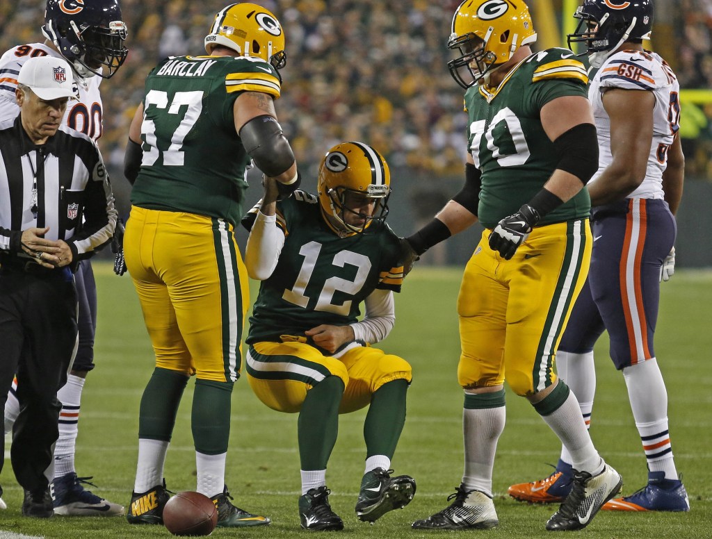 Green Bay Packers quarterback Aaron Rodgers is helped up by two of his offensive linemen, tackle Don Barclay (67) and guard T.J. Lang (70), after being injured on a play by Chicago Bears defensive end Shea McClellin during last Monday night’s game in Green Bay, Wis.
