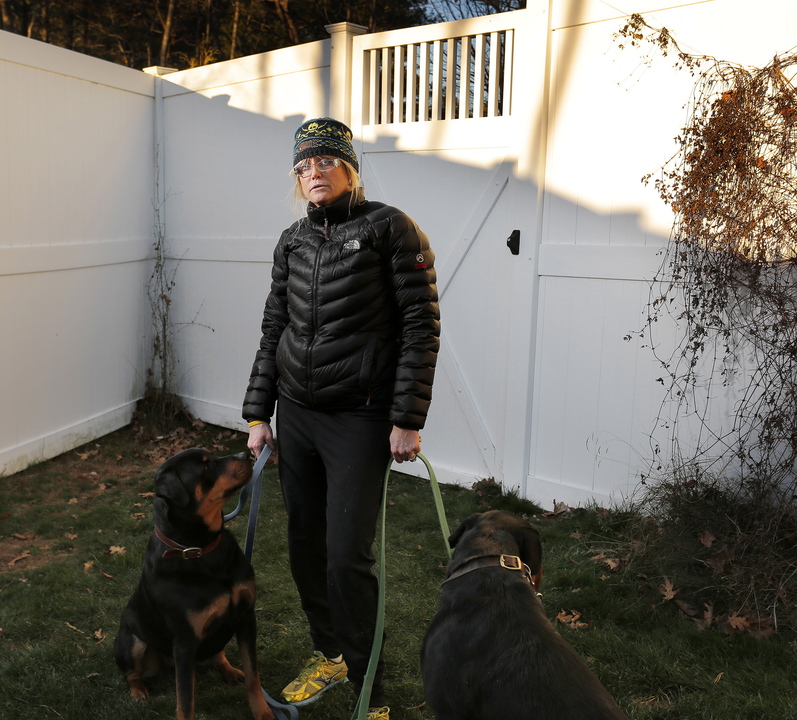 Toni Macquinn stands with her dogs, Sailor and Marina, in the backyard of her Old Orchard Beach home Wednesday, in the same spot where she says she was nearly hit by stray bullets from a hunter’s rifle.