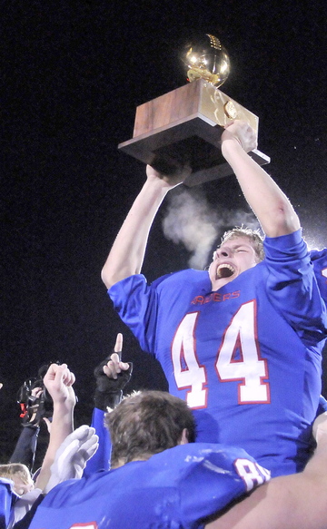 Kyle Flaherty hoists the Gold Ball while getting a boost from his Oak Hill teammates after the Raiders beat Bucksport 42-35 in the Class D state championship game.