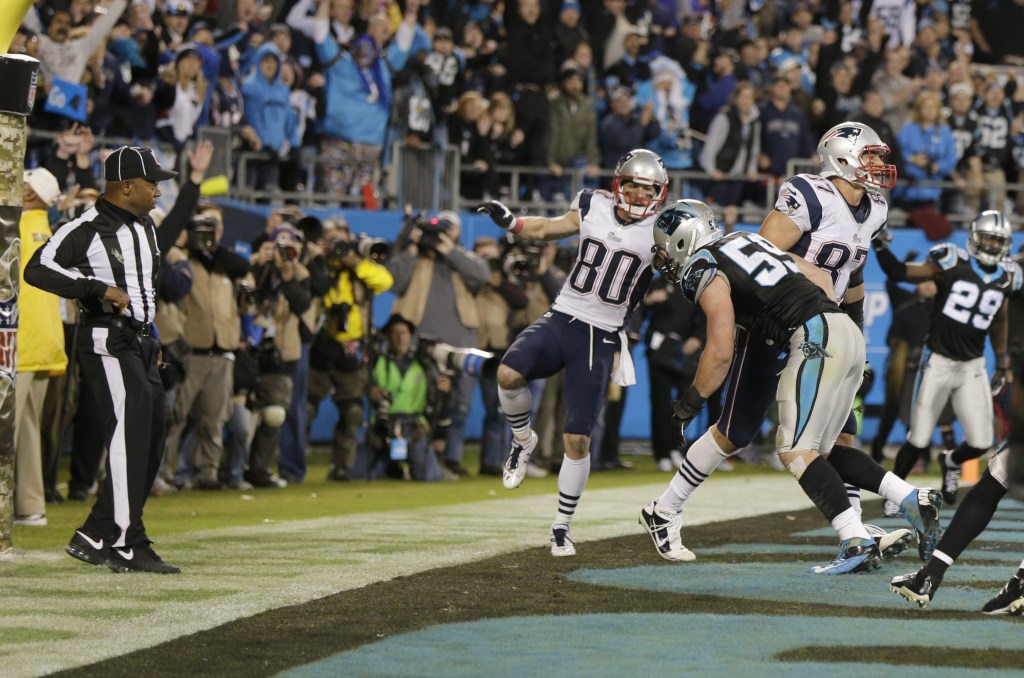 An official, left, reaches for his flag as Carolina Panthers’ Luke Kuechly (59) hits New England Patriots’ Rob Gronkowski (87) in the end zone on the last play of an NFL football game in Charlotte, N.C., Monday, Nov. 18, 2013. They ruled no penalty on the play.