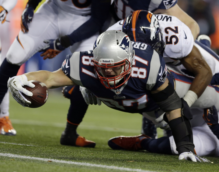 New England Patriots tight end Rob Gronkowski (87) stretches for extra yardage as he is brought down by Denver Broncos linebacker Wesley Woodyard (52) in the third quarter of an NFL football game Sunday, Nov. 24, 2013, in Foxborough, Mass.