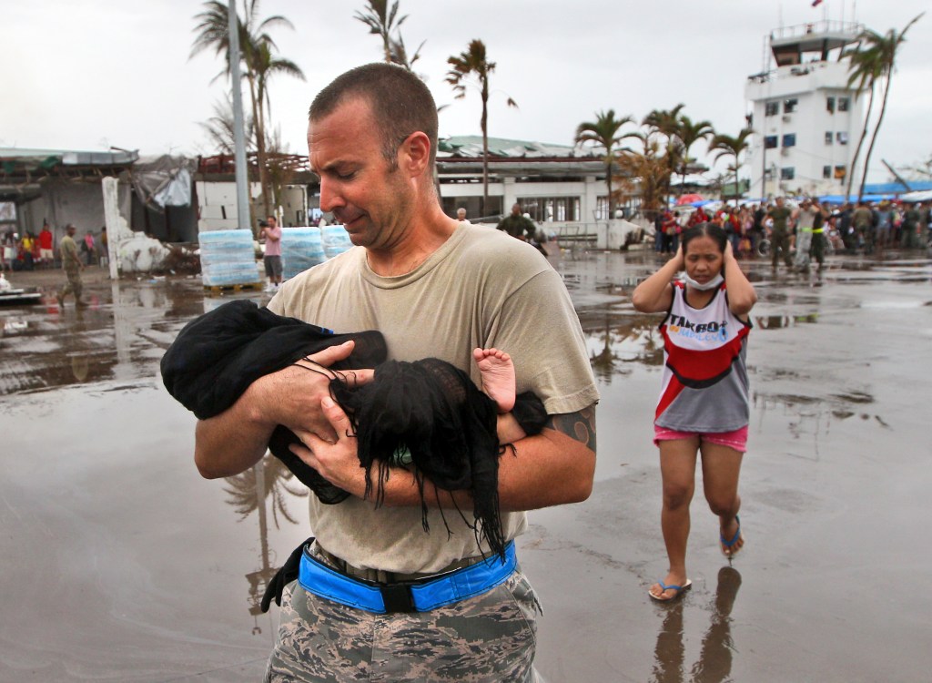 U.S. Air Force Sgt. Jody Dessicino of Egg Harbor, N.J., helps a mother carry her baby to board an evacuation flight at the airport in Tacloban, Philippines, on Friday.