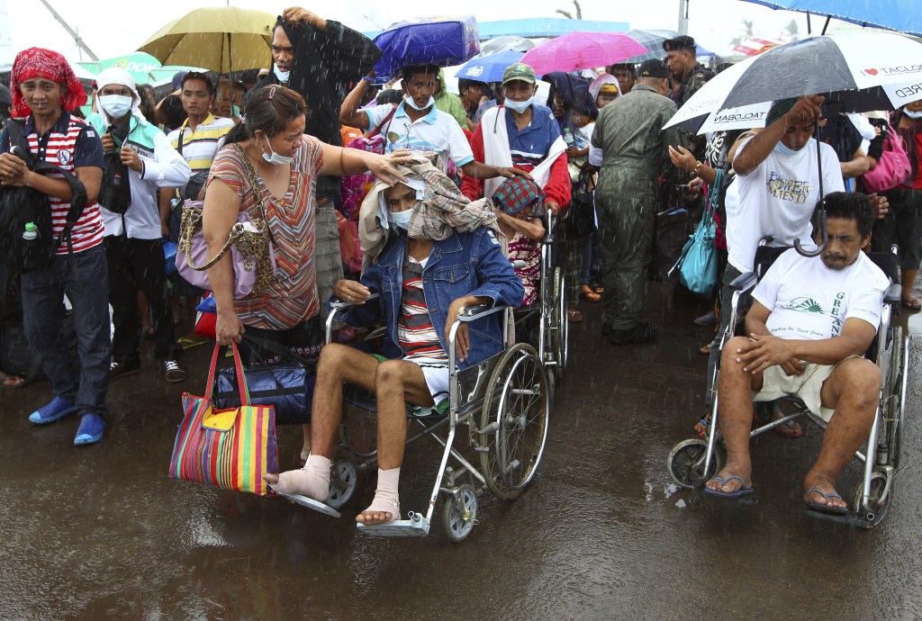 Typhoon Haiyan survivors, some injured, queue up in the rain to board an evacuation flight at the airport in Tacloban, Philippines, on Friday.