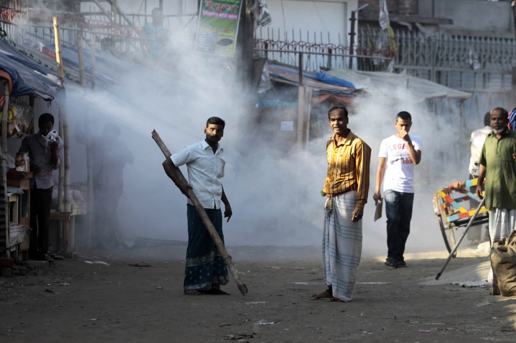 A Bangladeshi man armed with a bamboo stick reacts to the tear gas fired by police as people gathered for a protest in front of a closed factory in Gazipur, on the outskirts of Dhaka, Bangladesh, on Tuesday. Police fired rubber bullets and tear gas to disperse thousands of garment workers who rampaged through industrial towns in Bangladesh to protest the killing of two factory workers during a demonstration for higher wages. International retailers have been under pressure to improve conditions for workers.