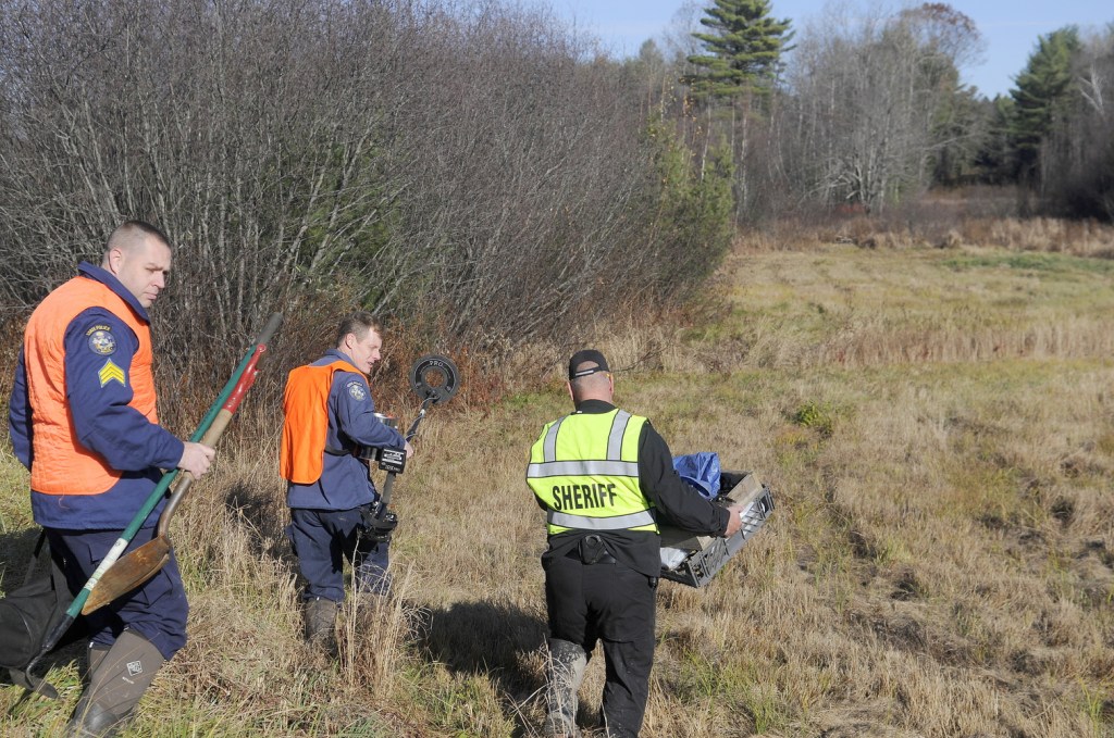 Maj. Ryan Reardon, right, of the Kennebec County Sheriff’s Office, carries evidence collection tools; state police Detective Terry James, center, lugs a metal detector; and state police Detective Sgt. Jason Richards carries hand tools into the woods of Manchester on Saturday afternoon to excavate skeletal remains discovered by hunters earlier in the day. The sheriff’s department was called just after 8 a.m. when a deer hunter encountered the bones about a half-mile up a dirt logging road from Puddledock Road, according to Reardon. The remains, believed to be of an adult, will be examined as they are recovered to determine an identity and a cause of death, Reardon said.