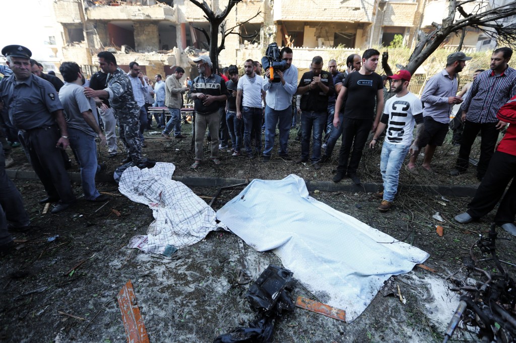 Lebanese people, gather around two dead bodies at the scene where two explosions have struck near the Iranian Embassy killing many, in Beirut, Lebanon, Tuesday, Nov. 19, 2013. The blasts in south Beirut’s neighborhood of Janah also caused extensive damage on the nearby buildings and the Iranian mission. The area is a stronghold of the militant Hezbollah group, which is a main ally of Syrian President Bashar Assad in the civil war next door. It’s not clear if the blasts are related to Syria’s civil war.