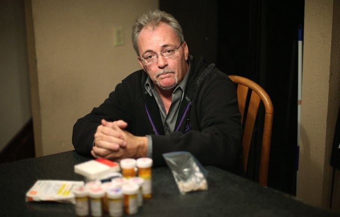 Mike Graham poses at his home in Manteno, Ill., with medications he used to take for degenerative disc disease. Graham began using medical marijuana about five years ago, which allowed him to stop using most of the pharmaceuticals for pain relief.