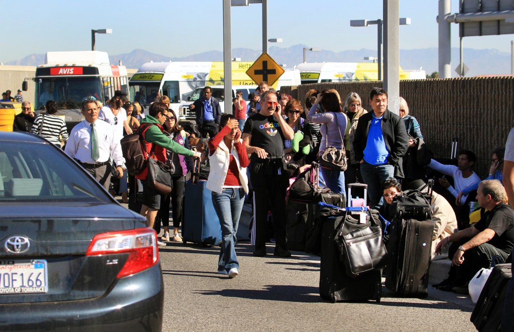 Passengers evacuate the Los Angeles International Airport on Friday after shots were fired there.