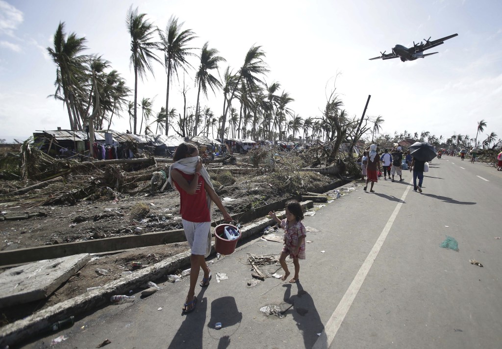 Survivors look up at a military C-130 plane as it arrives at typhoon-ravaged Tacloban city, Leyte province, in central Philippines on Monday. Stunned survivors of one of the most powerful typhoons ever to make landfall picked through the remains of their homes Monday and pleaded for food and medicine as the Philippines struggled to deal with what is likely its deadliest natural disaster.