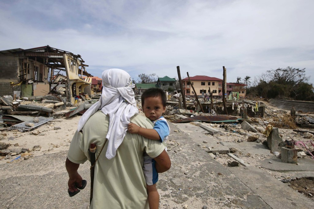 A man walks home with his son Monday, following Friday's devastating typhoon that lashed Hernani township, in eastern Samar province, in the central Philippines.