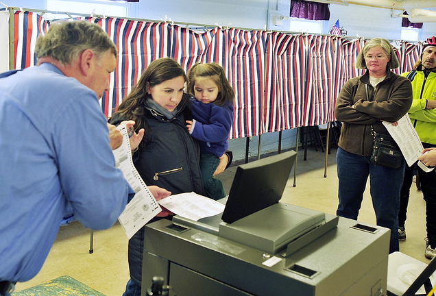 Voters wait patiently in line as Sarah Heeley, holding her daughter Charlotte Heeley, 2, gets help from a South Portland election clerk trying to get a voting machine to accept her ballots Tuesday. The warden at the American Legion Hall voting site for Ward 2, Precinct 1, said the machines were very slow processing the ballots, causing a long line of voters.