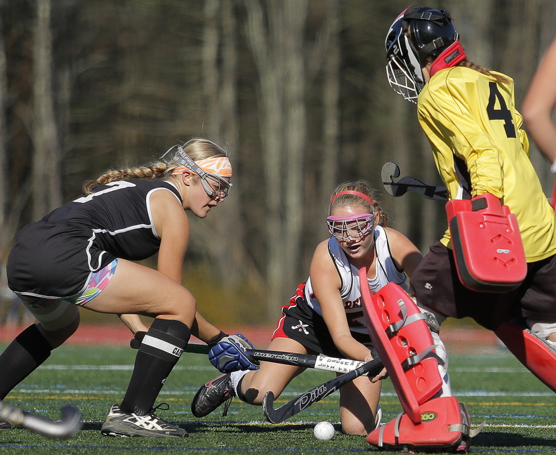 Skowhegan’s Mikayla Toth, left, battles Scarborough’s Ashley Levesque for control of the ball as Skowhegan goalie Leah Kruse gets in on the action during first half play in the Class A field hockey championship at Yarmouth High School Saturday, November 2, 2013.