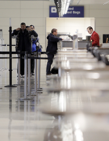 American Airlines agent Cody Dear helps John Mejia check in Monday for his flight to Miami at a nearly deserted Terminal D at Dallas-Fort Worth International Airport. A winter storm is blamed for 10 deaths in Texas.
