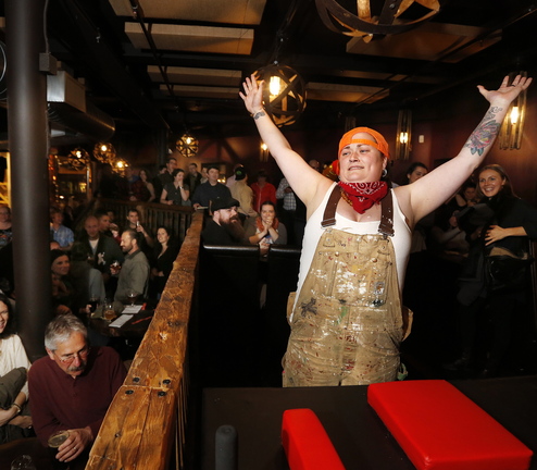 Kate Squibb, also known as Lumber Smack Sally, celebrates her first-round victory over Barrel Roll Barbie during an arm wrestling fundraiser Thursday at In’finiti.