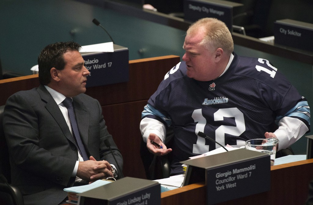 Mayor Rob Ford has a conversation with Councillor Giorgio Mammoliti at city hall in Toronto on Thursday. Ford is threatening to take legal action against former aides who told police of their concerns about his drug use and drunken driving.