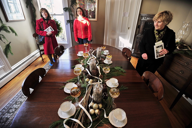 Patricia Neja, from left, Suzanne Ambler and Allie Libby view a centerpiece made by Amy Young Pierce during the Holiday Home Tour in Portland on Saturday.