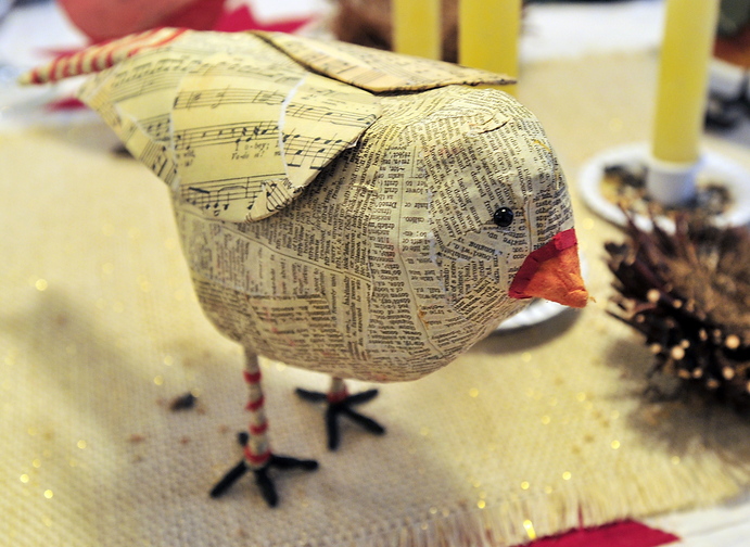 Interior designer Kim Corwin created a dining table centerpiece that featured a flock of papier-mache birds, like this one, complete with birdseed candlestick holders.