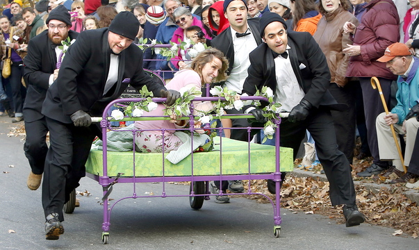 Wendy Herrick, owner of Wendy Herrick Floral Designs and Tuxedo Rentals, clings to her “Bed of Roses” Saturday as teammates push it to the finish line to win this year’s Rolling Slumber Bed Races in Brunswick.