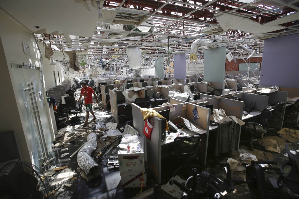 A worker walks inside a damaged call center office in Palo town, Leyte province, central Philippines Tuesday, Nov. 19, 2013. More than 4 million people have been displaced and need food, shelter and water after Typhoon Haiyan hit the country on Nov. 8.