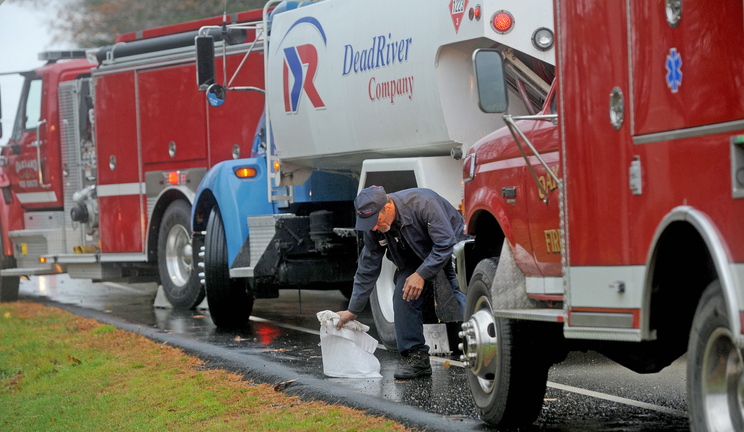 Shawn Mullen, 46, a delivery driver for Dead River Company, mops up spilled fuel in front of 256 Belgrade Road in Oakland on Friday. The delivery truck apparently leaked oil for about six miles through Oakland while making deliveries.