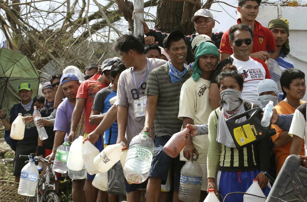 Typhoon survivors line up to get fuel from an abandoned filling station Thursday in Tacloban city in central Philippines. Aid has been slow to reach the people displaced by the storm that tore across several islands in the eastern Philippines last Friday.