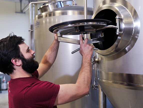 Ian McConnell, an owner and brewmaster of Banded Horn Brewing Co., checks his primary fermenter on Friday. The arrival of the company is seen as a positive economic sign for Biddeford.