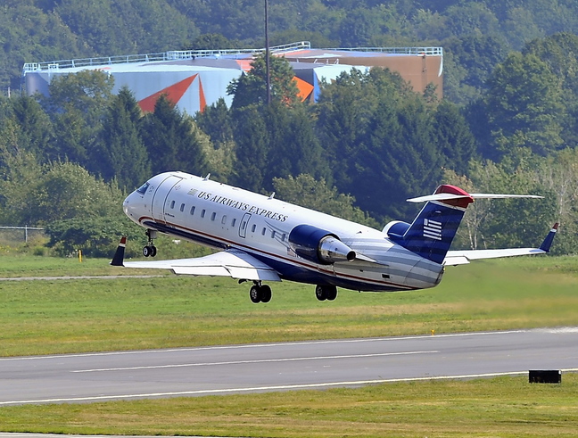US Airways Express Flight 3722 takes off for Philadelphia from the Portland International Jetport and flies over the oil tanks in South Portland. US Airways, the largest carrier in Portland, will be merging with American Airlines.