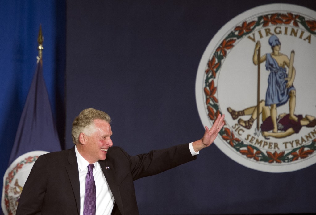 Va. Governor-elect Democratic Terry McAuliffe waves next to the flag of Virginia as he appears onstage to address his supporters at his victory party in Tysons Corner, Va., Tuesday, Nov. 5, 2013.