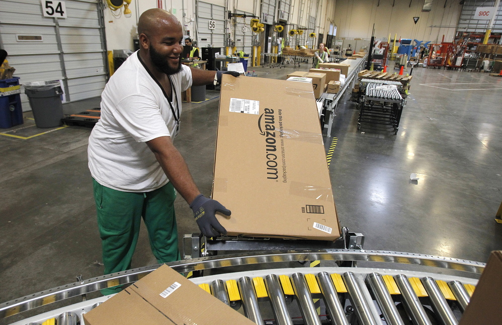 Leacroft Green places a package on the belt at an Amazon.com fulfillment center in Goodyear, Ariz. Amazon is teaming up with the U.S. Postal Service to deliver packages on Sundays. The service will debut in New York and Los Angeles.