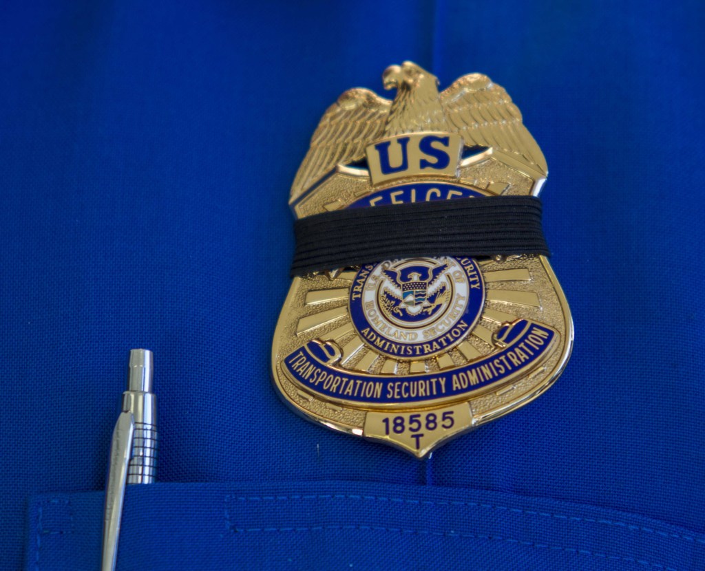 A Transportation Security Administration employee wears a black ribbon over his badge on Saturday, Nov. 2, 2013, in Los Angeles International Airport. A gunman armed with a semi-automatic rifle opened fire at the airport on Friday, killing a Transportation Security Administration employee and wounding two other people in an attack that frightened passengers and disrupted flights nationwide.