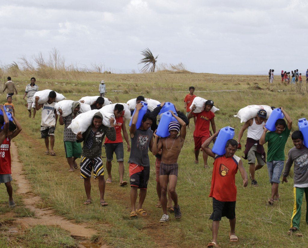 Survivors carry relief supplies unloaded by a U.S. Navy helicopter Saturday to villagers isolated by last week’s typhoon Haiyan on Manicani island in the Philippines.