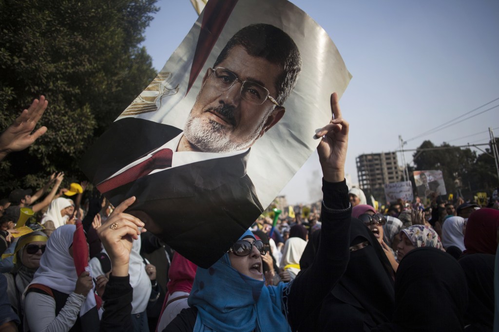 An Egyptian woman holds a portrait of ousted Egyptian President Mohammed Morsi during a protest Friday in Cairo. The trial of Morsi opens Monday, presenting serious challenges for the military-backed authorities. Days before the trial, the location of where he will be tried has not been announced for security reasons. His supporters threaten massive protests that may disrupt the proceedings. And in his anticipated first public appearance after four months in secret military detention, Morsi could turn his trial on charges of inciting murder into a platform for indicting the coup, giving more vigor to the opposition.